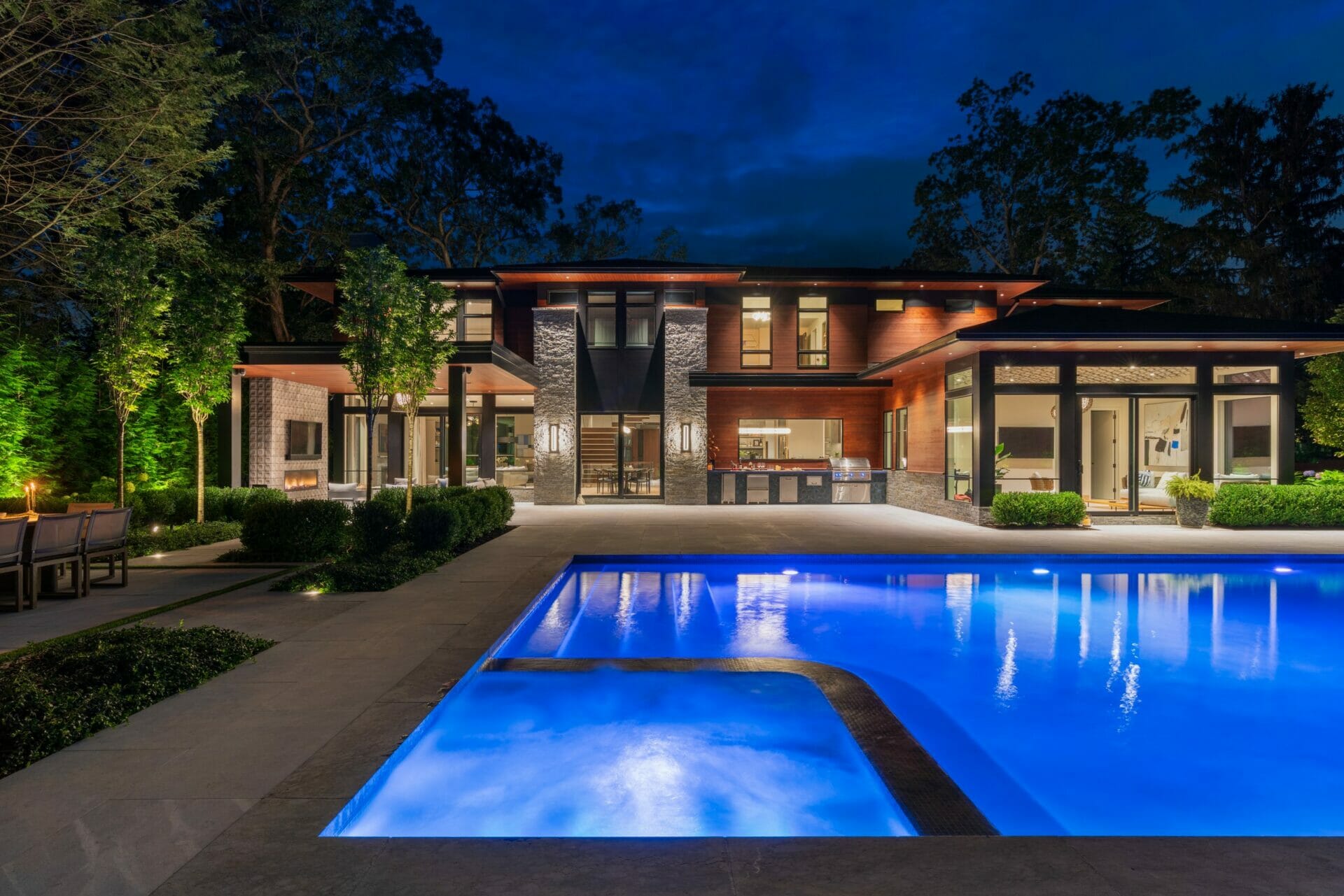 A pool at night with a beautiful home in the background.